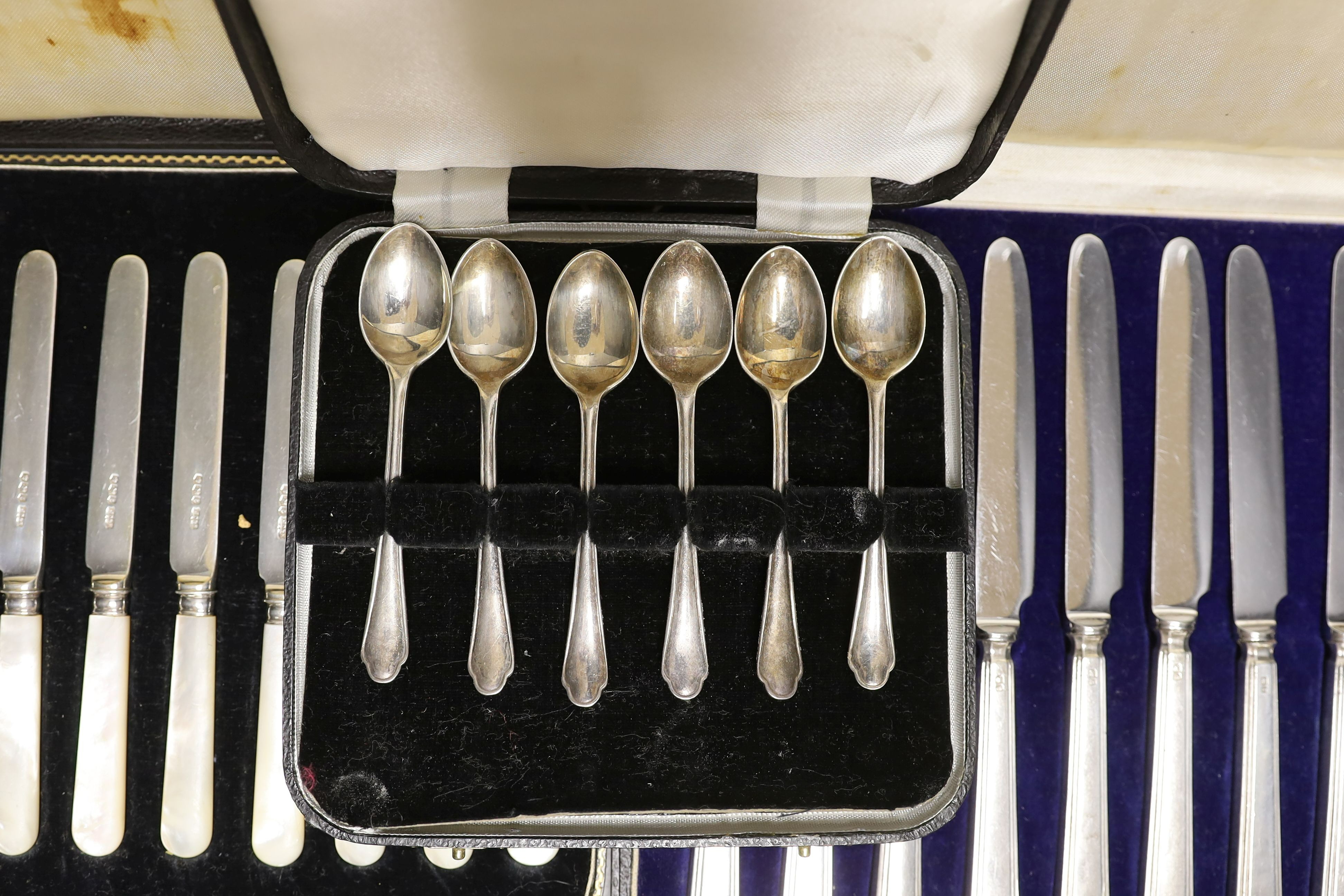 Two cased sets of silver or mother of pearl handled tea knives and a cased set of six silver teaspoons.